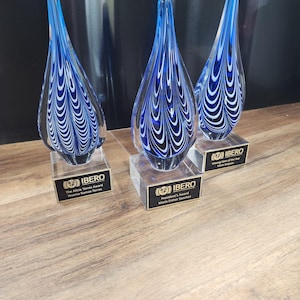 Trio of stunning hand-blown glass teardrop awards with intricate blue and white swirl patterns, each mounted on a clear base with a custom engraved nameplate. Perfect for honoring excellence, leadership, or appreciation in corporate or nonprofit events. Elegant and artistic recognition pieces that serve as both awards and decorative keepsakes. Ideal for employee recognition or commemorative ceremonies.