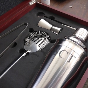 Personalized martini cocktail set in a rosewood finish gift box featuring stainless steel bar tools including a shaker engraved with initials 'CT', strainer, jigger, stirrer, and ice tongs. The tools are securely nestled in custom-cut foam for a premium presentation. Ideal for weddings, groomsmen gifts, Father’s Day, anniversaries, or home bar essentials. A stylish and functional gift for cocktail enthusiasts or mixology lovers.