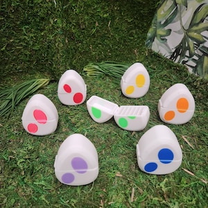 May include: Set of seven white triangular containers with different colored dots. The containers are open and show a green interior with a small compartment.