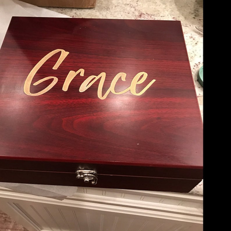 Custom engraved rosewood finish gift box with the name 'Grace' in a gold color-filled cursive font. This personalized wooden box is ideal for cocktail sets, bar tools, keepsakes, or special gifts. The elegant gold script stands out against the deep red wood grain, making it perfect for bridesmaid gifts, birthdays, weddings, anniversaries, or holiday gifting. Features a secure metal clasp and premium craftsmanship for a luxurious presentation.