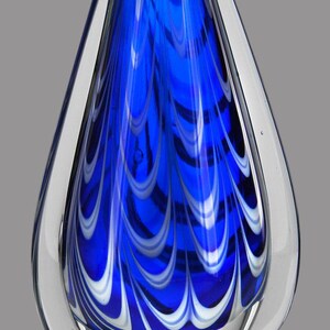 A blue glass award with white swirls. The award is on a clear acrylic base with a black plaque that reads 'JOHN TOMEY SERVANT LEADERSHIP AWARD PLANNET MARKETING, INC. 2018'.