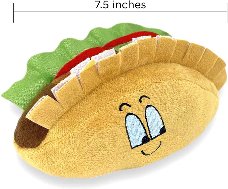 May include: A plush toy shaped like a taco with a smiling face. The taco is 7.5 inches long and has a brown shell, green lettuce, and a red and white filling.