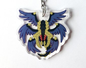 May include: A purple and gold winged creature keychain with a silver chain and clasp. The creature has red eyes and a black body.