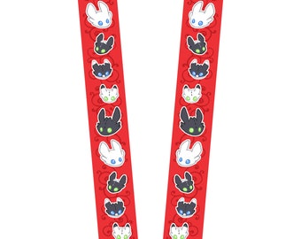 Op de afbeelding: Een rode lanyard met afwisselend zwarte en witte drakengezichten. De draken hebben groene ogen en blauwe accenten.
