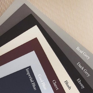 Puede incluir: Una colecci&oacute;n de muestras de tela en varios colores, incluyendo blush, claret, azul fr&iacute;o, azul imperial, &eacute;bano, gris oscuro y gris claro.