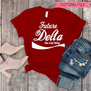 May include: Red t-shirt with white text that reads "Future Delta the real thing" in a Coca-Cola inspired font.