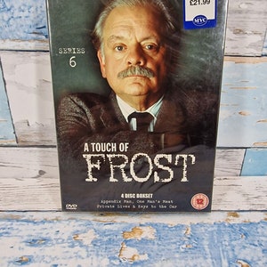 Pode incluir: Box de DVD de "A Touch of Frost: Série 6" com David Jason. A capa apresenta um retrato do ator com o título da série em letras grandes. Inclui quatro discos com episódios como "Appendix Man" e "One Man's Meat".