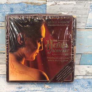 May include: A brown box with a gold border and a woman's face on the front. The box is labeled "The Henna Body Art Kit" and includes everything you need to create stunning temporary body tattoos.