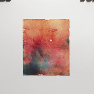 May include: A framed abstract watercolour painting with shades of red, orange, and blue.