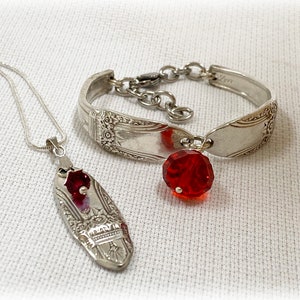 Puede incluir: Un conjunto de collar y pulsera de cuchara de plata con cuentas de vidrio rojas. El collar y la pulsera están hechos de cubiertos antiguos.