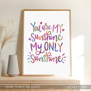 May include: A framed print with the words "You are MY Sunshine, MY ONLY Sunshine" in colorful script. The text is in shades of blue, green, pink, and yellow. The frame is a light brown color. The words "FRAME IS NOT INCLUDED" are at the bottom.
