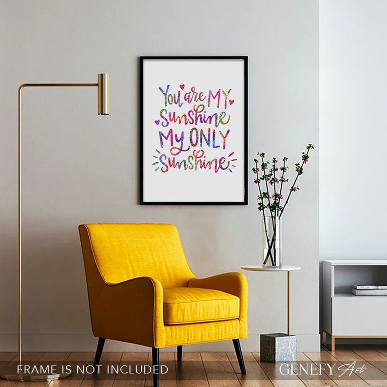 May include: A framed art print with the words "You are MY Sunshine MY ONLY Sunshine" in colorful script. The print is displayed in a room with a yellow armchair, a gold floor lamp, and a side table with a vase of flowers.