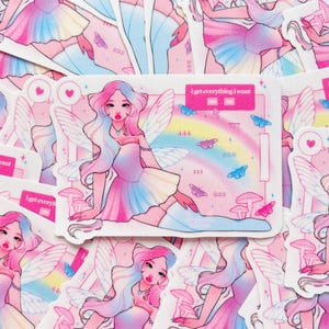 Op de afbeelding: Een rechthoekige sticker met een fee met lang roze en blauw haar, vleugels en een pastelkleurige jurk. De achtergrond bevat een regenboog, paddenstoelen, vlinders en de tekst "I get everything I want" met "yes" en "no" vakjes, plus de getallen 444, 888, 111 en 222.