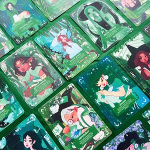 Peut inclure: Un ensemble de cartes de tarot avec des illustrations de figures mystiques dans des tons de vert, de bleu et de rose. Chaque carte pr&eacute;sente des &oelig;uvres d'art et du texte uniques, avec des phrases comme "shooting star" et "touch grass."