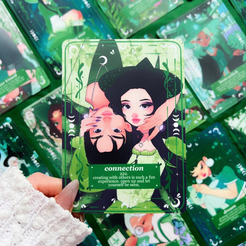 Peut inclure: Une carte de tarot verte avec une illustration de deux personnes s'embrassant, le mot "connection" et le num&eacute;ro "222". La carte est entour&eacute;e d'autres cartes de tarot avec des motifs verts et blancs. Le texte dit: cr&eacute;er avec les autres est une exp&eacute;rience si amusante. Ouvrez-vous et laissez-vous voir.