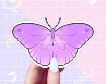 May include: A sticker featuring a purple butterfly with heart accents. The butterfly has gradient wings and is held by a hand against a pink and purple grid background. The sticker has the text "aianaiye illustration".