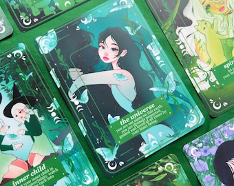 May include: A collection of tarot cards with illustrations and text. The cards feature images of women, butterflies, and nature elements in shades of green, blue, and purple. Text on the cards includes phrases like "the universe" and "inner child."
