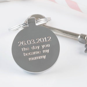 May include: Silver key chain with a round charm that says "26.03.2012 the day you became my mummy".