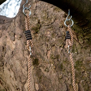 May include: Two brown rope swings hanging from a tree branch. Each swing has a silver hook and a black plastic connector.