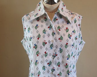 May include: A white sleeveless blouse with a collared neckline and a button-up front. The blouse features a floral print with small, colorful flowers and a geometric pattern.