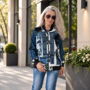 Könnte beinhalten: Eine Bomberjacke mit einer Kombination aus blauen Denim-Einsätzen, weißem Stoff mit blauem Blumenmuster und schwarzen Netz-Akzenten. Die Jacke verfügt über einen durchgehenden Frontreißverschluss sowie einen schwarzen Rippstrickkragen, -bündchen und -saum.