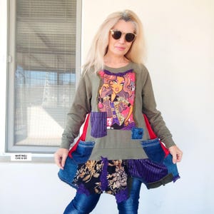 Peut inclure: Haut à manches longues vert olive avec un imprimé d'une femme de dessin animé. Le haut présente des patchs en denim et en tissu à motifs, des accents rouges et des poches en jean. Le bas du haut a un design superposé avec des tissus floraux et rayés.