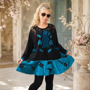 May include: A long-sleeved black tunic featuring a round neckline, intricate black lace detailing on the upper chest, and a vibrant teal blue satin-like skirt section adorned with black floral embroidery and matching teal blue fabric accents.