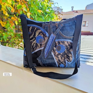 May include: A denim shoulder bag with a butterfly design. The butterfly is made of blue denim, sequins, and blue fabric. The bag has a black strap and a black body. The text "MARTINELI CHIC & GO" is visible.