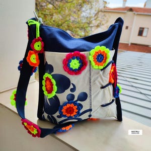 K&ouml;nnte beinhalten: Eine wei&szlig;e Keramik-Tasse mit schwarzem Henkel und dem Text "But First, Coffee" in fetter, schwarzer Schrift. Die Tasse steht vor einem verschwommenen Hintergrund, der eine gem&uuml;tliche Umgebung suggeriert.