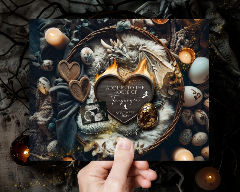 May include: A wooden heart-shaped sign with the text "Adding to the House of Targaryen" and the date "November 2024". The sign is surrounded by a nest of dragon eggs, a dragon figurine, and candles.