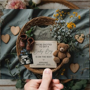 May include: A baby announcement card with a blue background and a wicker basket filled with flowers, a teddy bear, baby shoes, and a sonogram. The card reads "We're excited to say a Baby Boy is on the way! Arriving January 2025".