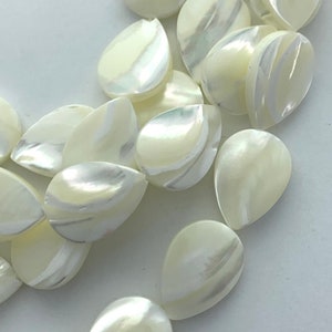 May include: Close-up of pearlescent, teardrop-shaped beads. The beads have a creamy white base color with iridescent swirls of silver and green. These beads are ideal for jewelry making and crafting.