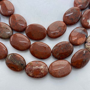 15x20mm Oval African Red Jasper Gemstone Beads. 15” strand of flat oval Jasper beads, 20 per strand.  Red with some matrix.