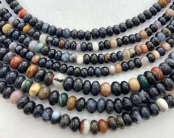 May include: Close-up of several strands of gemstone beads. The beads are a mix of colors, including black, brown, white, and blue. The beads are strung together to create a necklace or bracelet.