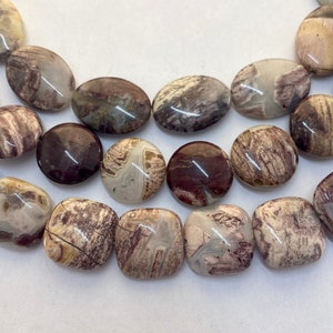 May include: Close-up of a strand of natural stone beads. The beads are a mix of oval and square shapes, in shades of brown, cream, and gray. The stones have a marbled appearance with unique patterns.