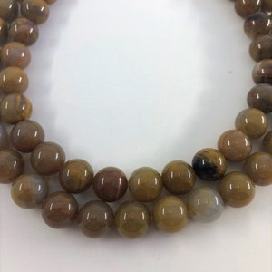 12mm Petrified Wood Beads. 15” strand of yellow-brown round beads, roughly 33 beads per strand. Wooden Agate Beads.