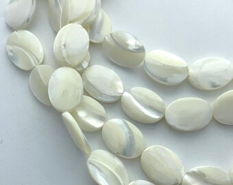 Peut inclure: Gros plan sur un fil de perles ovales blanc cassé avec des surfaces irisées et nacrées. Les perles sont disposées en plusieurs rangées, mettant en valeur leur texture lisse et leurs subtiles variations de couleur. Idéal pour la création de bijoux.