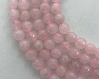 May include: Close-up of strands of faceted rose quartz beads. The beads are a soft pink colour and are strung together with pink thread. The beads have a geometric, multi-faceted surface.
