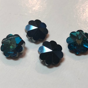 以下が含まれることがあります： ターコイズと濃い青色の、花型のファセットビーズが4つ。各ビーズはスカラップエッジと、光を反射する多面的な表面を持っています。ジュエリー作りや工芸に適しています。