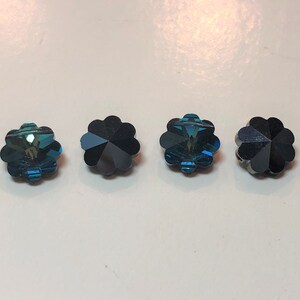 以下が含まれることがあります： ターコイズと濃い青色の、花型のファセットビーズが4つ。各ビーズは、光を反射する多弁のデザインです。これらの装飾ビーズは、ジュエリー作りやクラフトプロジェクトに適しています。