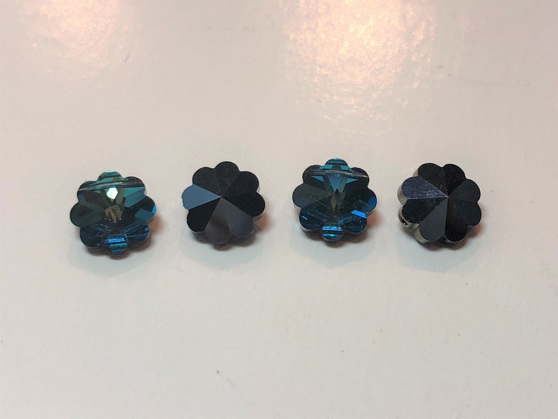 以下が含まれることがあります： ターコイズと濃い青色の、花型のファセットビーズが4つ。各ビーズは、光を反射する多弁のデザインです。これらの装飾ビーズは、ジュエリー作りやクラフトプロジェクトに適しています。