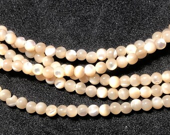 Peut inclure: Gros plan de plusieurs brins de perles rondes et lustrées de couleur pêche. Les perles ont une subtile irisation, reflétant la lumière. Les brins sont disposés en couches, créant une sensation de profondeur. Idéal pour la création de bijoux.