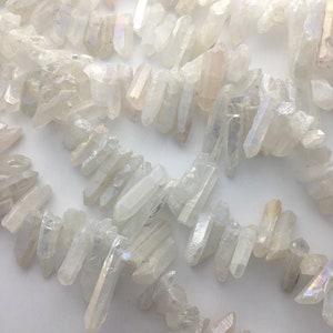 May include: Strands of clear, raw quartz crystal beads. The crystals are irregular in shape and have a slightly iridescent sheen. The beads are strung together, creating a necklace or bracelet design. The crystals are white and translucent.