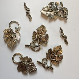 May include: Silver-toned metal leaf-shaped toggle clasps and matching bars. The clasps feature detailed leaf and vine designs, with a loop on one end and a bar on the other. Ideal for jewelry making or craft projects.