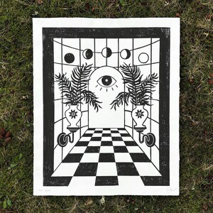 a large portrait oriented linocut print in black ink on white paper. in the center is an arched doorway with a large open eye in the center staring right at you. 2 vases with suns on them on either side of the door, each with three large palm leaves