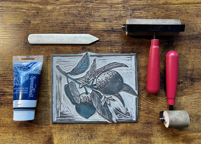 The linoleum block, ink, and rollers used to make this print. The block is a reverse image of the print.