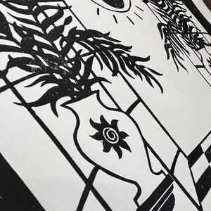closeup of the middle section of the print. the small suns on each greek style vase have a spiral in the center and their rays are curved. this gives the impression of clockwise movement. each vase is on a narrow stand branching out from the wall