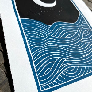 A closeup of the waves on the print, highlighting the blue ink and white lines between where the paper is showing through. The edges of the paper are torn rather than cut, giving a rustic artful look.
