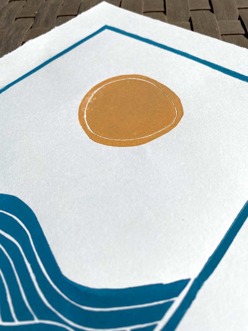 Closeup on the yellow orange sun. it has a white line around the edge and is not quite a perfect circle. The edges of the paper are torn rather than cut, giving a rustic artful look.