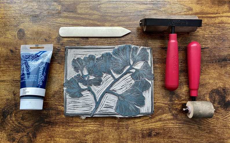 The linoleum block, ink, and rollers used to make this print. The block is a reverse image of the print.